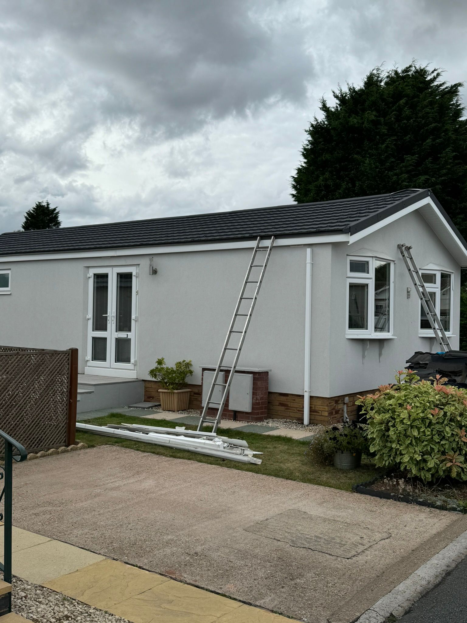 Renovated white park home with new black tiled roof nearing completion