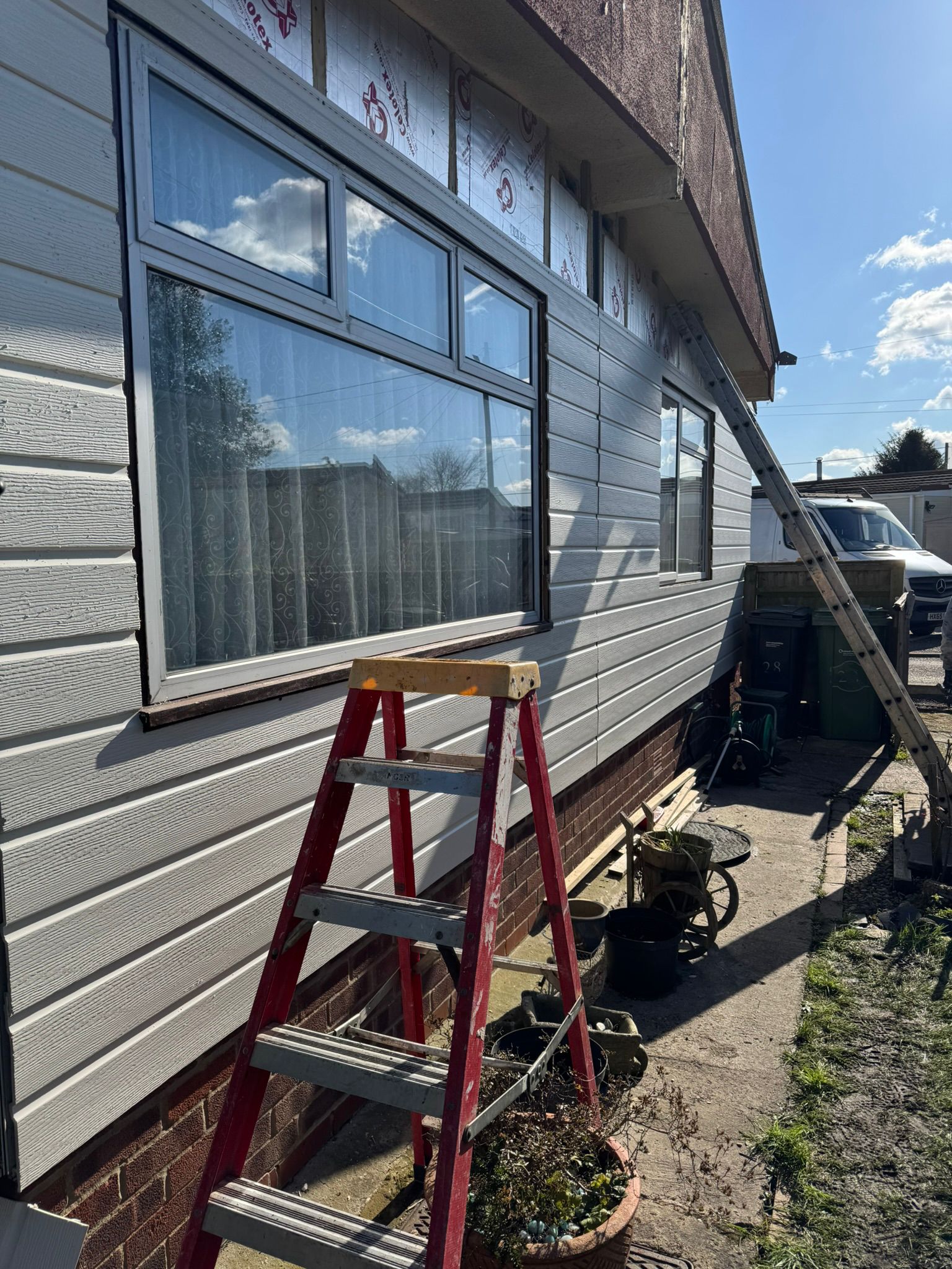 Grey cladding installation in progress with ladder against the wall