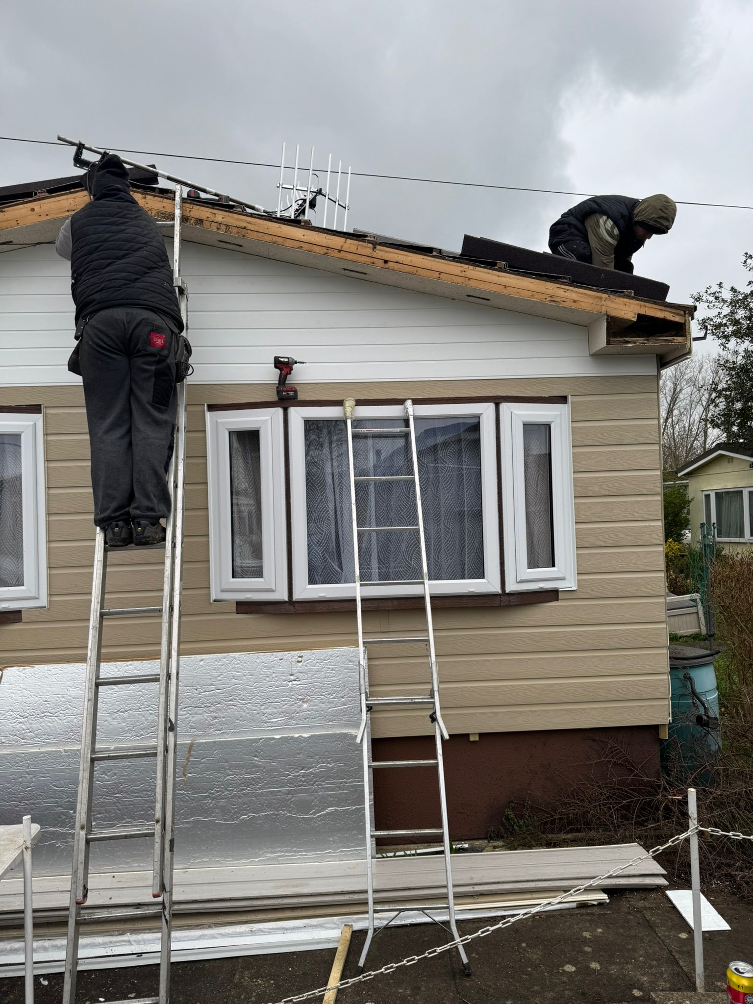 Two-man team stripping and re-felting a park home roof