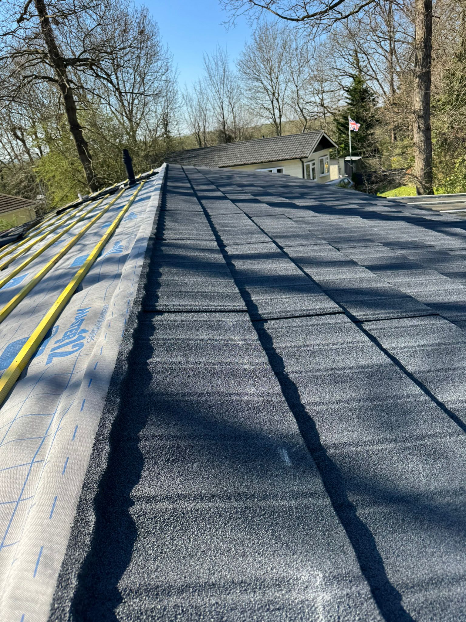 Lightweight roof tiles being laid over breathable membrane on a sunny day